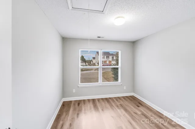 a view of an empty room with wooden floor and a hallway