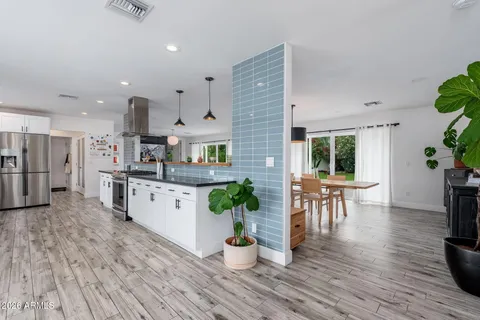 an open kitchen with white cabinets and wooden floor