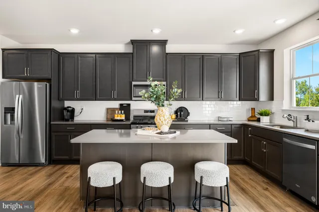 a kitchen with kitchen island granite countertop a sink cabinets and stainless steel appliances