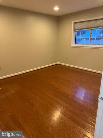 a view of an empty room with wooden floor and closet