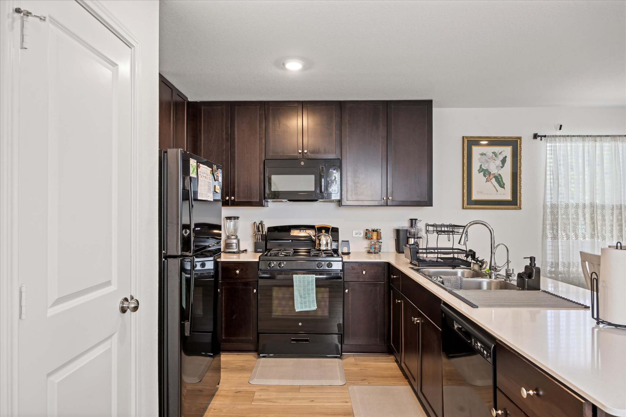 36 Trinity Circle Lockhart, TX 78644 - Photo 3 of 24 Rich dark cabinetry and stone countertops anchor this modern culinary workspace with wood-style flooring.