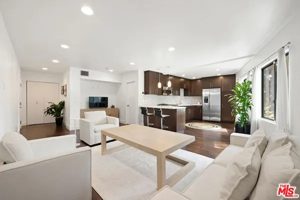 a living room with furniture a large window and kitchen view