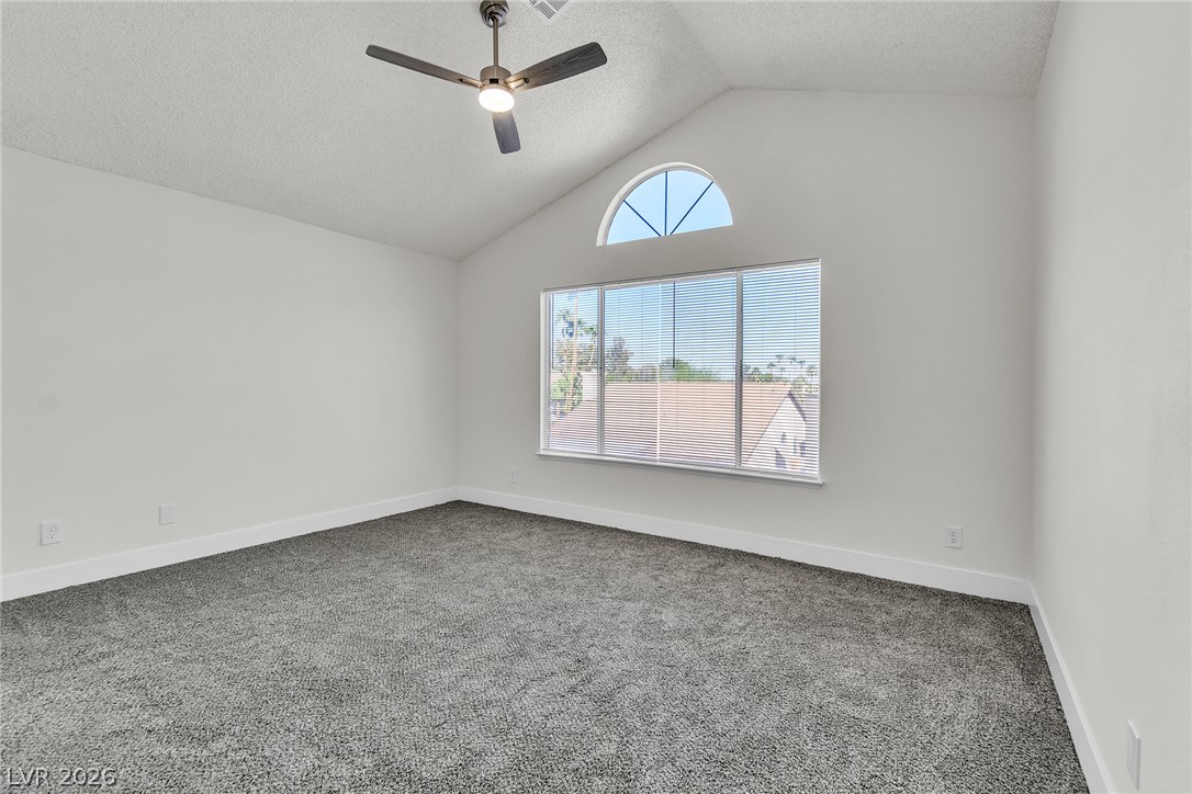 370 Rushing Creek Court Henderson, NV 89014 - Photo 18 of 32 Plush carpeting anchors this bedroom under soaring vaulted ceilings and a half-round transom window.