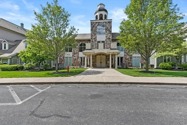 a front view of a building with a garden and trees