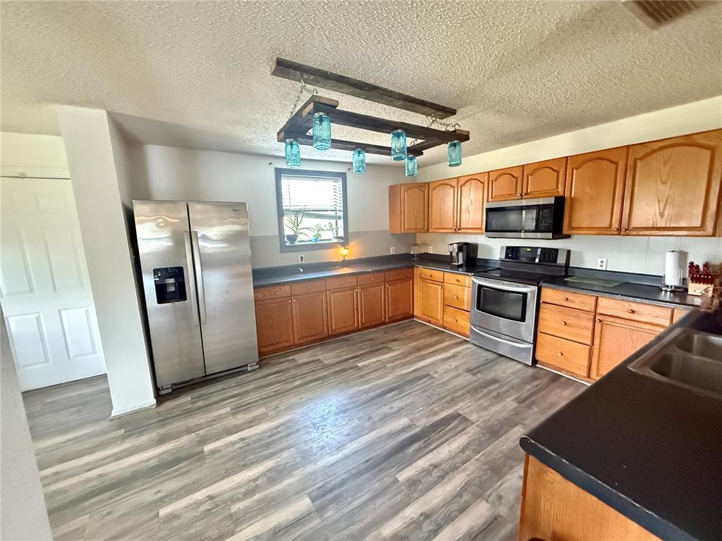 439 Corbett Road Lithia, FL 33547 - Photo 7 of 27 a kitchen with stainless steel appliances granite countertop a refrigerator a stove top oven a sink and dishwasher