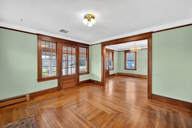 a view of an empty room with window and wooden floor