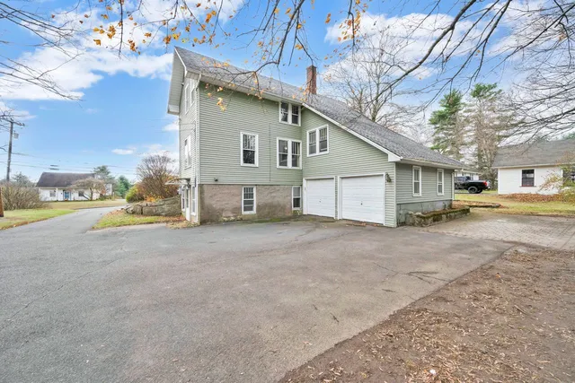 a view of a house with a yard and large tree