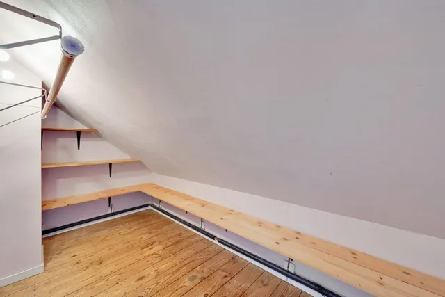 a view of an empty room with wooden floor and stairs
