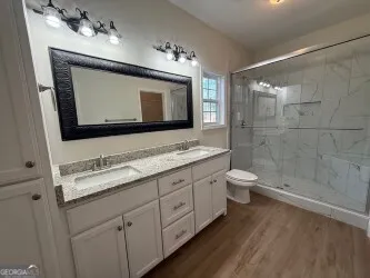 a bathroom with a toilet sink double vanity and mirror