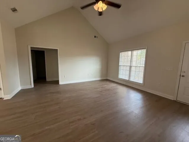 an empty room with wooden floor and windows