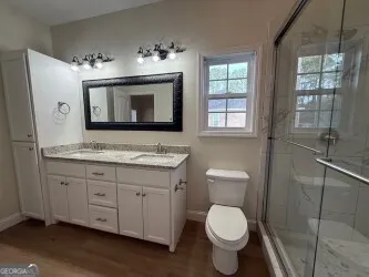 a bathroom with a granite countertop toilet sink and mirror
