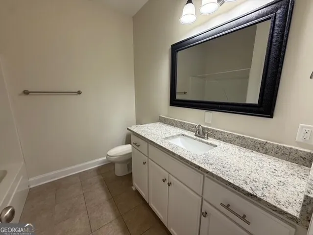 a bathroom with a granite countertop toilet sink and mirror
