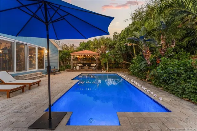 a view of a pool with a table and chairs under an umbrella