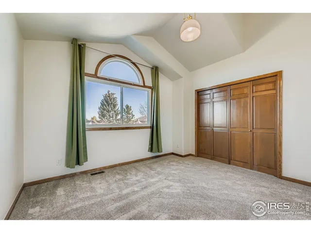 a view of an empty room with wooden floor and window