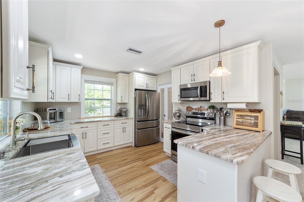 9040 Southwest 209th Circle Dunnellon, FL 34431 - Photo 19 of 55 a kitchen with granite countertop a refrigerator oven a sink dishwasher and white cabinets with wooden floor