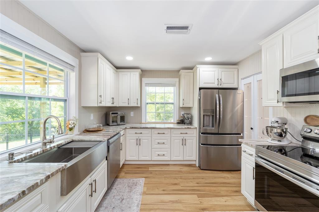 9040 Southwest 209th Circle Dunnellon, FL 34431 - Photo 20 of 55 a kitchen with a refrigerator a sink dishwasher a stove and white cabinets with wooden floor
