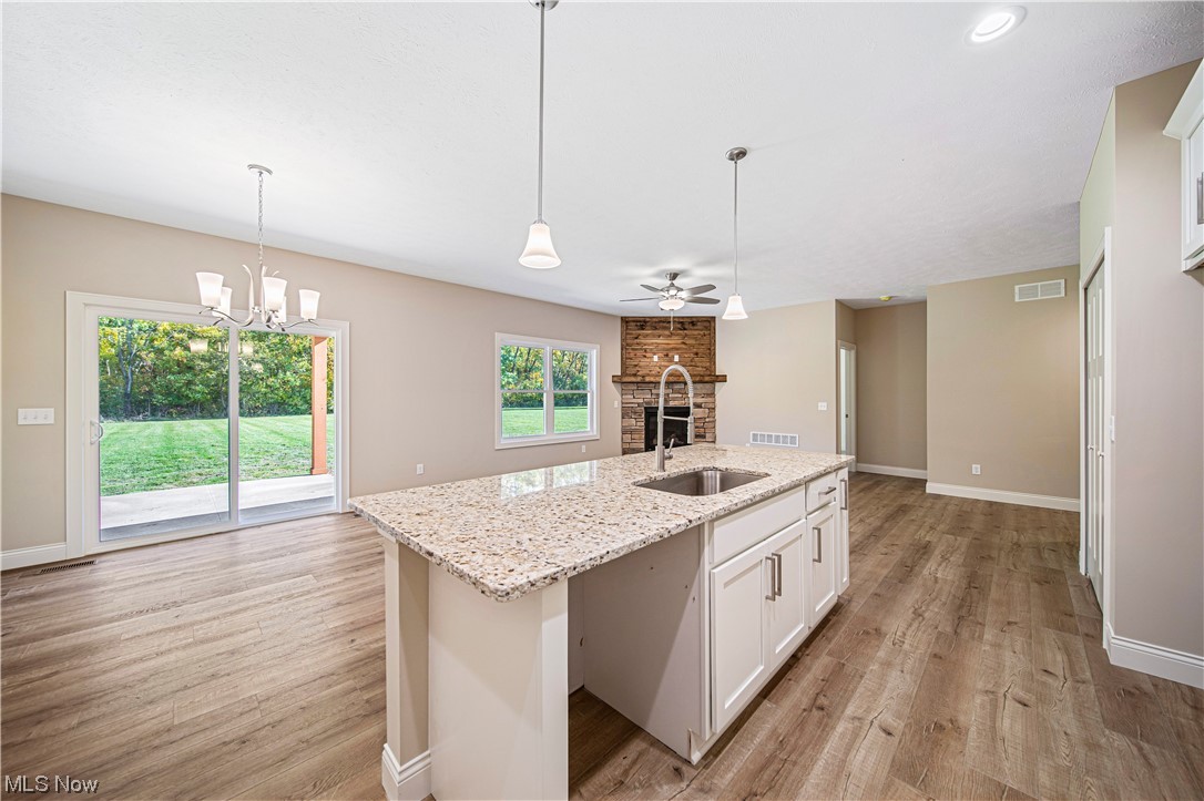 1745 Green Road Madison, OH 44057 - Photo 13 of 35 Kitchen with light hardwood / wood-style floors, hanging light fixtures, white cabinets, and a brick fireplace
