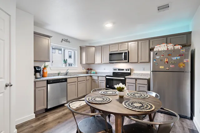 a kitchen with stainless steel appliances granite countertop a sink a stove a refrigerator cabinets and dining table