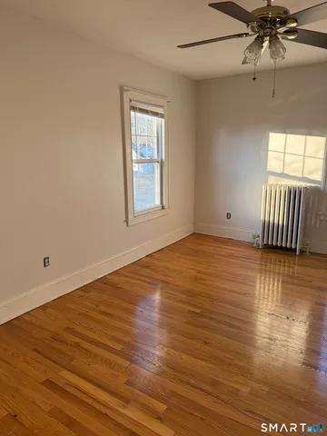 an empty room with wooden floor fan and windows