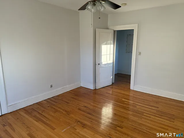 an empty room with wooden floor closet and windows