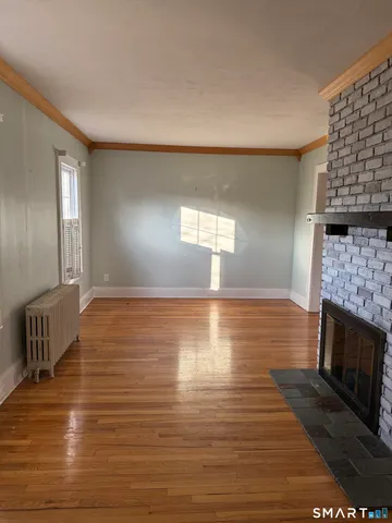 a view of empty room with wooden floor and fireplace