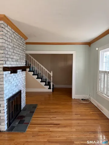 a view of an empty room with wooden floor and a fireplace