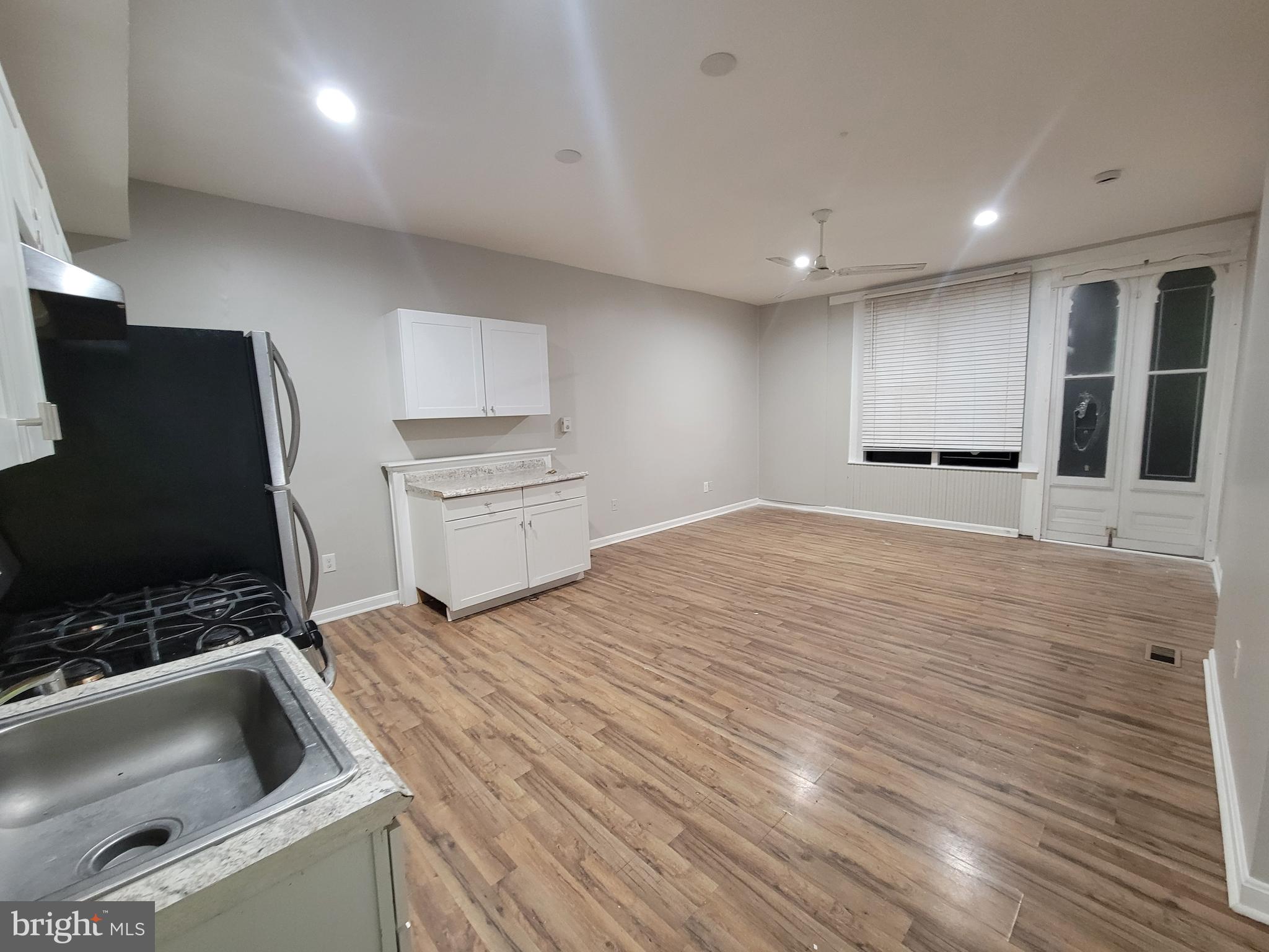 1217 Hollins Street, Unit 1 Baltimore, MD 21223 - Photo 3 of 6 a kitchen with granite countertop a sink and a stove top oven