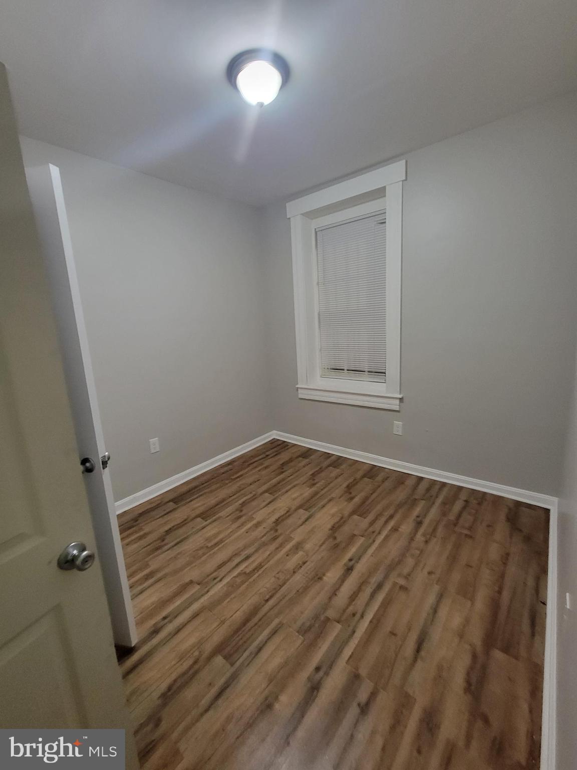 1217 Hollins Street, Unit 1 Baltimore, MD 21223 - Photo 4 of 6 an empty room with wooden floor and window