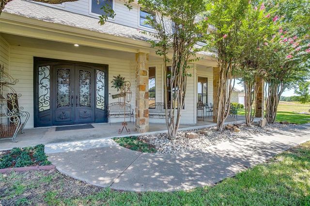 a view of a house with brick walls plants and large trees