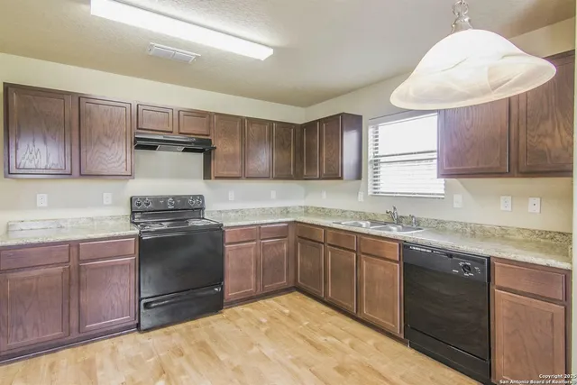 a kitchen with granite countertop a sink stainless steel appliances and cabinets