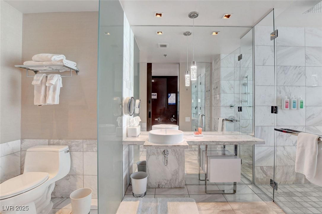 4381 West Flamingo Road, Unit 1206 Las Vegas, NV 89103 - Photo 12 of 27 Bathroom featuring tile walls, a shower stall, vanity, toilet, and tile patterned floors