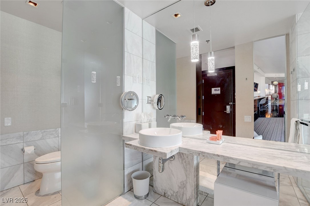 4381 West Flamingo Road, Unit 1206 Las Vegas, NV 89103 - Photo 13 of 27 Full bath with tile walls, tile patterned floors, a sink, toilet, and a walk in shower