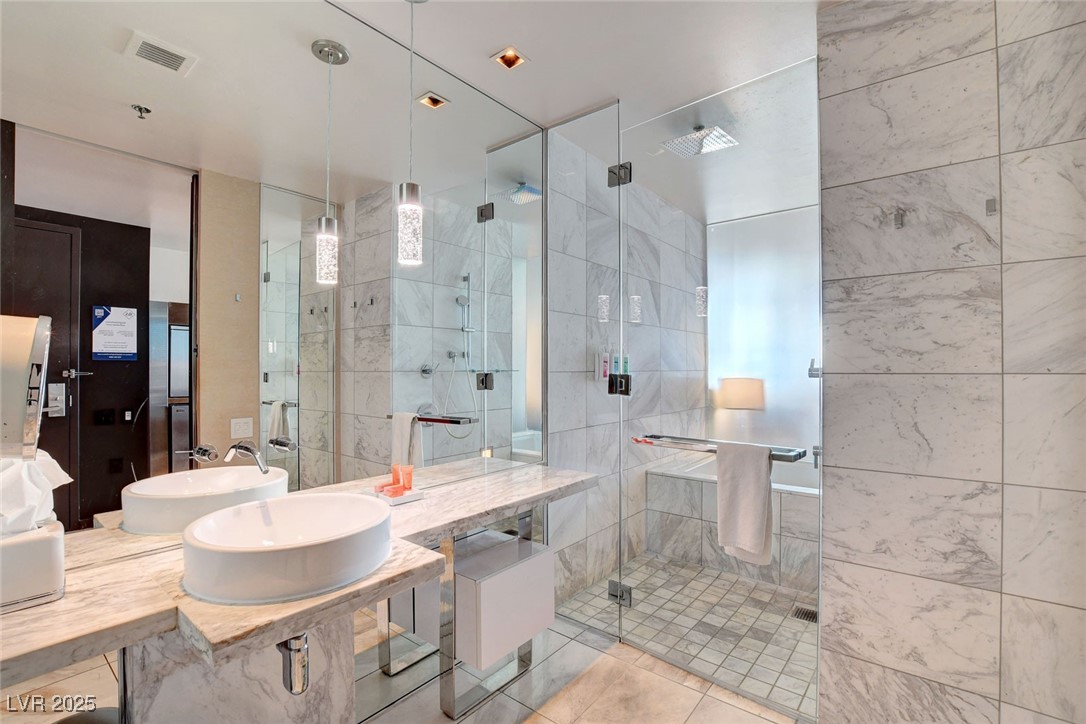 4381 West Flamingo Road, Unit 1206 Las Vegas, NV 89103 - Photo 14 of 27 Bathroom featuring a stall shower, a sink, tile patterned floors, and tile walls
