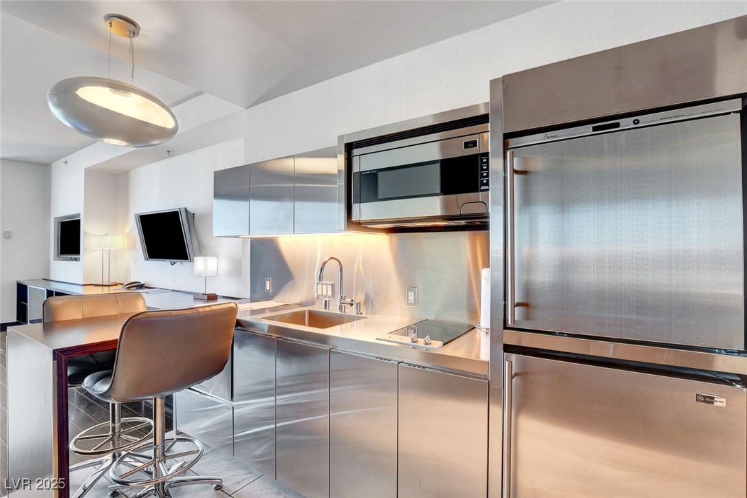 4381 West Flamingo Road, Unit 1206 Las Vegas, NV 89103 - Photo 3 of 27 Kitchen with appliances with stainless steel finishes, stainless steel countertops, modern cabinets, a sink, and decorative light fixtures