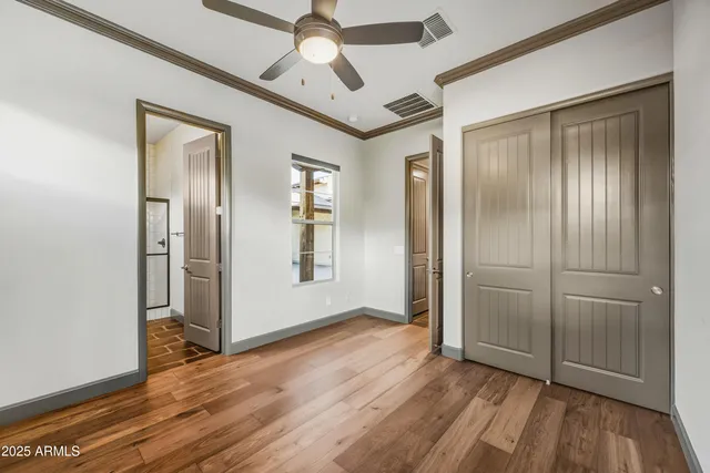 an empty room with wooden floor a ceiling fan and windows