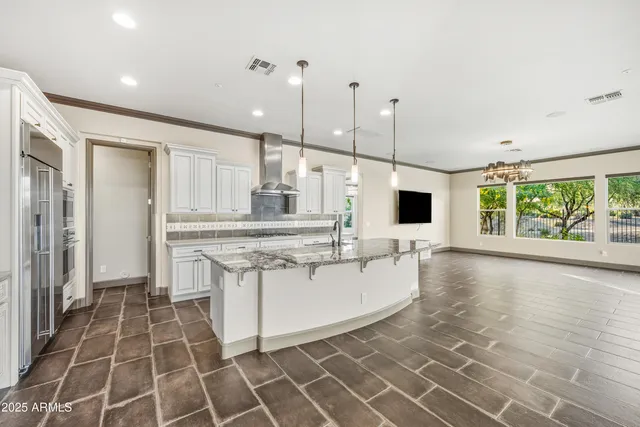 a large kitchen with kitchen island a sink a stove a dining table and a flat screen tv