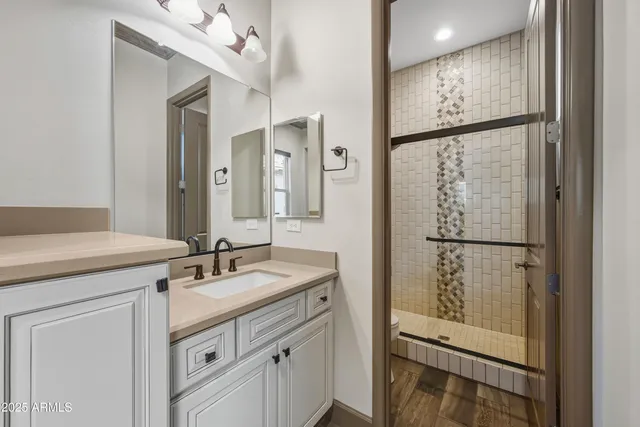 a bathroom with a sink a mirror a vanity and a shower