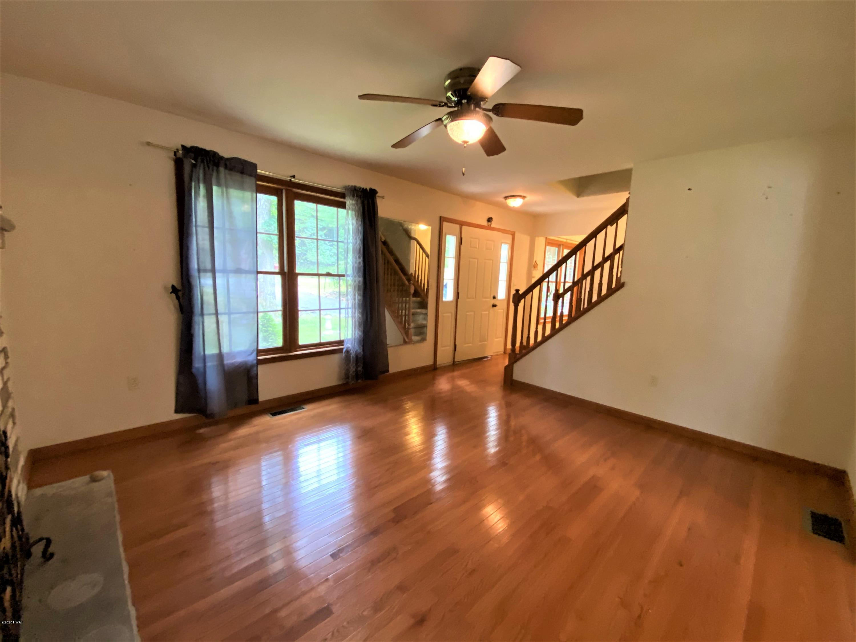 111 Beecher Road Dingmans Ferry, PA 18328 - Photo 4 of 25 a view of an empty room with wooden floor and a window