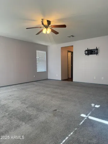 a view of an empty room with window and chandelier fan