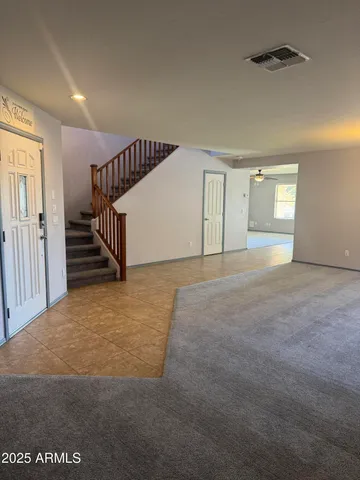 a view of an empty room with stairs and a window