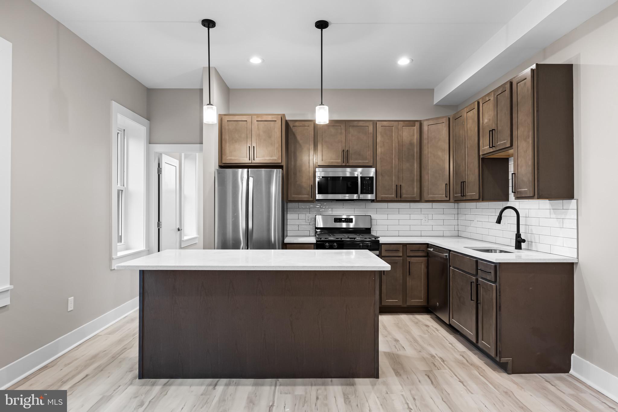 400 South Conkling Street, Unit 1 Baltimore, MD 21224 - Photo 2 of 18 a kitchen with stainless steel appliances granite countertop a sink a stove a refrigerator cabinets and wooden floor