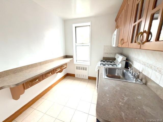 59-30 108th Street, Unit 6J Queens, NY 11368 - Photo 13 of 22 Kitchen featuring white appliances, glass insert cabinets, light tile patterned floors, and tasteful backsplash