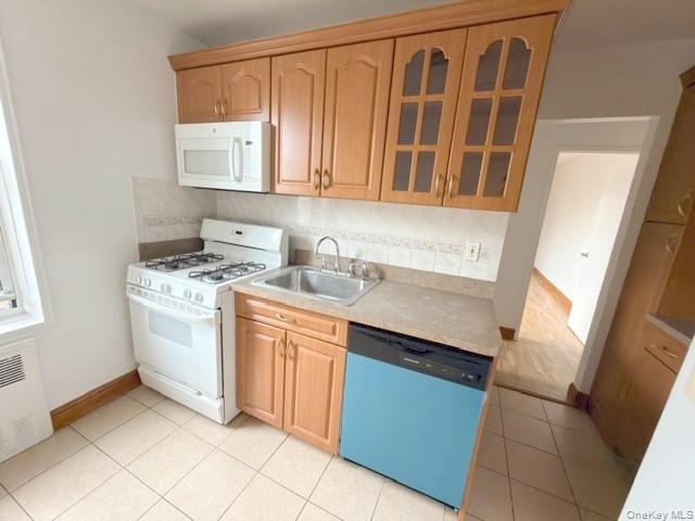 59-30 108th Street, Unit 6J Queens, NY 11368 - Photo 14 of 22 Kitchen with white appliances, glass insert cabinets, tasteful backsplash, light countertops, and radiator heating unit