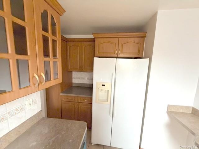 59-30 108th Street, Unit 6J Queens, NY 11368 - Photo 15 of 22 Kitchen with white fridge with ice dispenser, tasteful backsplash, light countertops, and glass insert cabinets