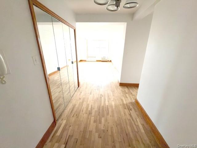 59-30 108th Street, Unit 6J Queens, NY 11368 - Photo 5 of 22 Hallway with light wood finished floors, a chandelier, and radiator heating unit