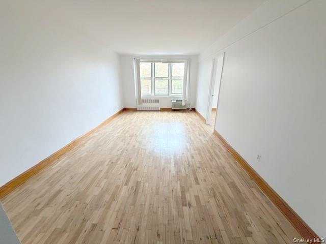 59-30 108th Street, Unit 6J Queens, NY 11368 - Photo 6 of 22 Empty room with light wood finished floors and radiator