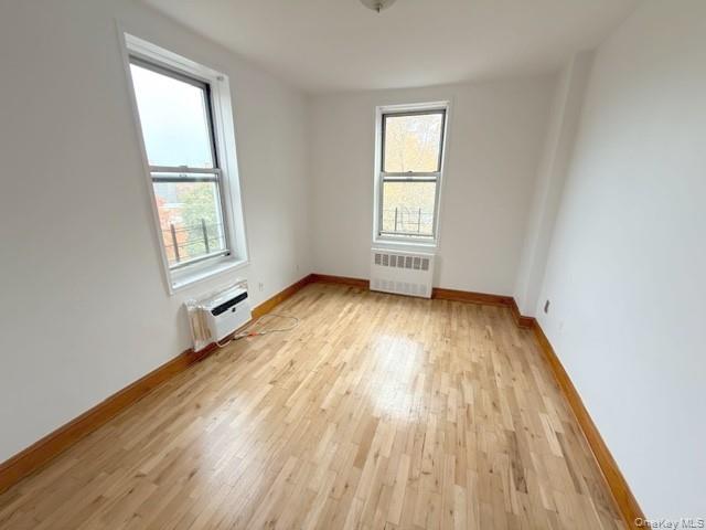 59-30 108th Street, Unit 6J Queens, NY 11368 - Photo 7 of 22 Unfurnished room featuring light wood-type flooring, radiator heating unit, and a wall unit AC