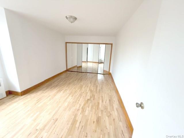 59-30 108th Street, Unit 6J Queens, NY 11368 - Photo 10 of 22 Spare room featuring baseboards and light wood-type flooring