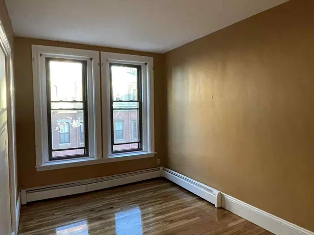 a view of an empty room and wooden floor and a window