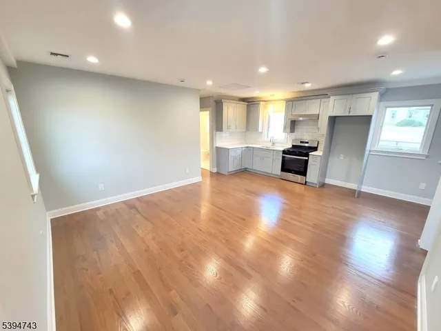 a view of kitchen with stainless steel appliances wooden floor and large window